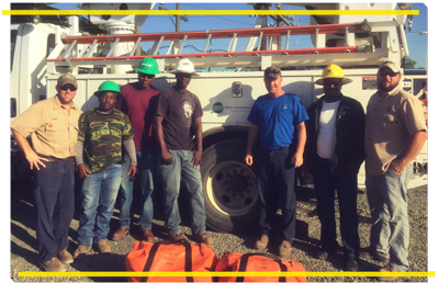 Linemen standing in front of bucket truck.